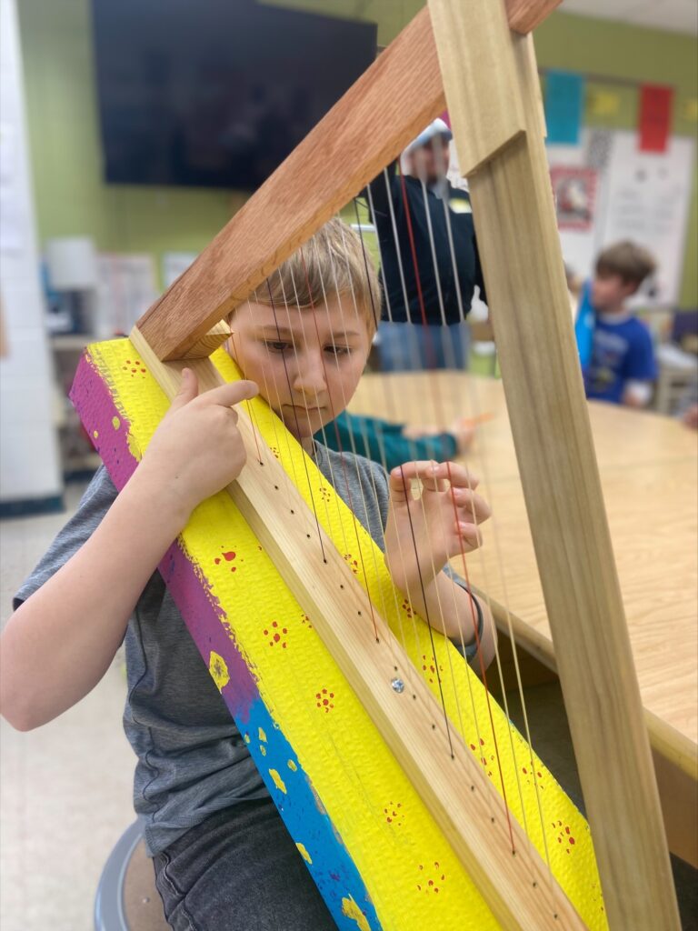 Student pluck strings on his new harp