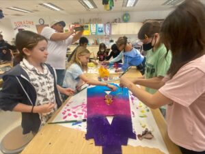 Students paint with vibrant colors the bases for their harps